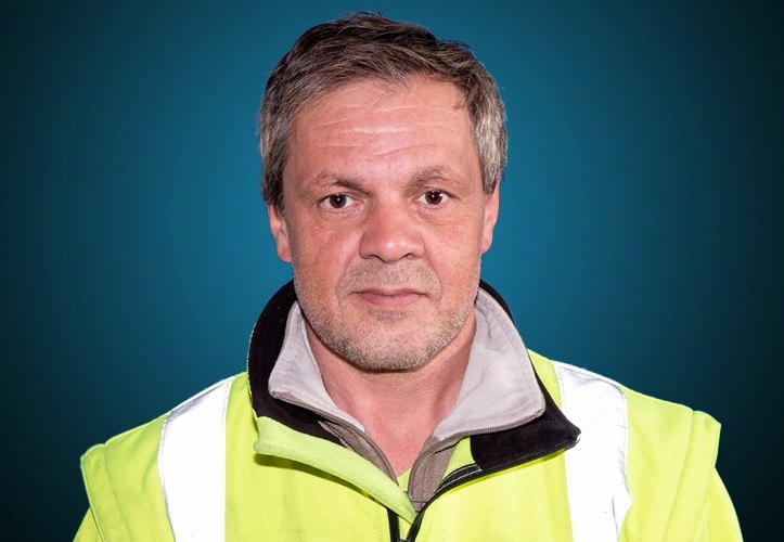 Portraitfoto eines Lagermitarbeiters von CAPITAL Baustoffe vor einem blauem Hintergrund