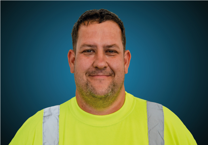 Portraitfoto eines Lagermitarbeiters von CAPITAL Baustoffe vor einem blauem Hintergrund