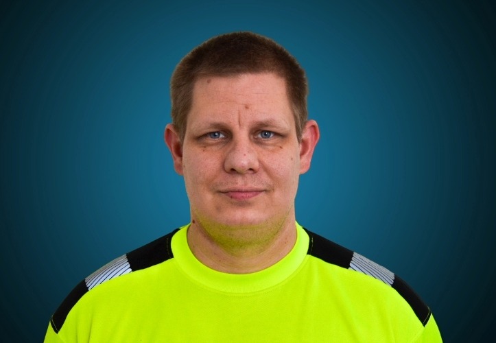 Portraitfoto eines Lagermitarbeiters von CAPITAL Baustoffe vor einem blauem Hintergrund