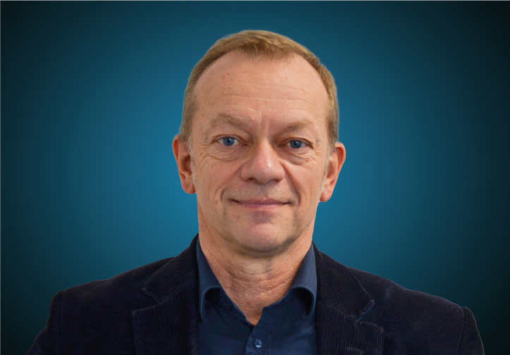 Portraitfoto des Vertriebsleiters Ausbau / Trockenbau von CAPITAL Baustoffe vor einem blauem Hintergrund