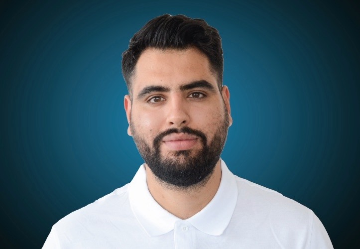 Portraitfoto eines Fachberaters für Ausbau im Innendienst von CAPITAL Baustoffe vor einem blauem Hintergrund