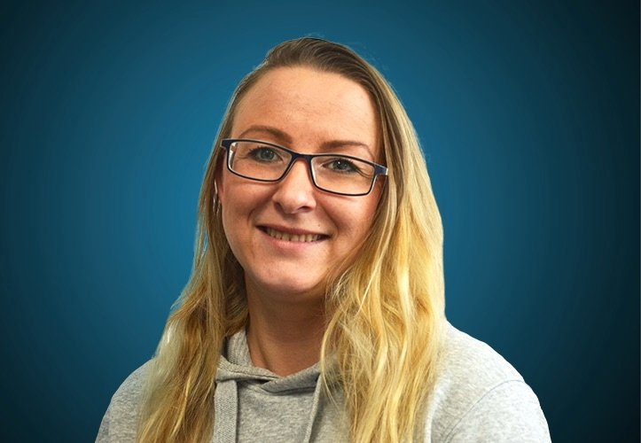 Portraitfoto einer Kundendienst-Mitarbeiterin von CAPITAL Baustoffe vor einem blauem Hintergrund