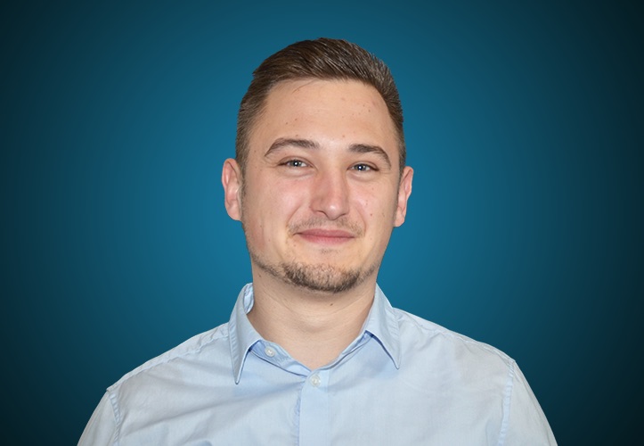 Portraitfoto eines Fachberaters für Hochbau im Außendienst von CAPITAL Baustoffe vor einem blauem Hintergrund