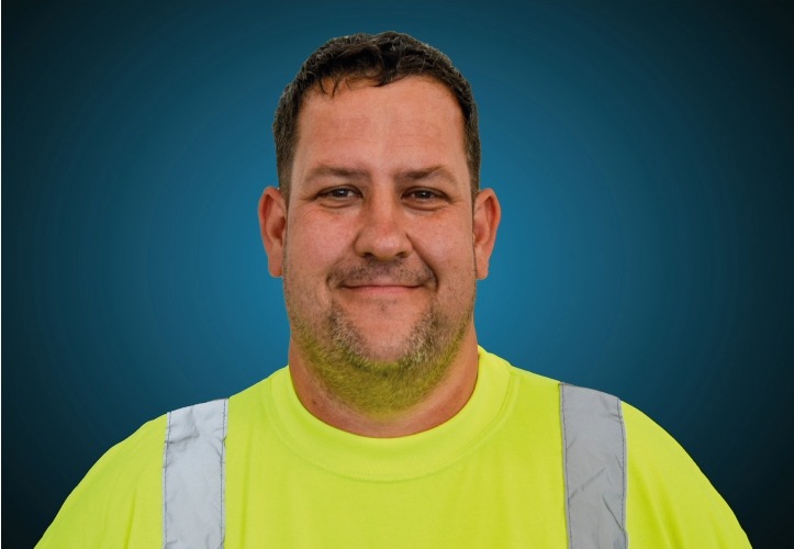 Portraitfoto eines Lagermitarbeiters von CAPITAL Baustoffe vor einem blauem Hintergrund