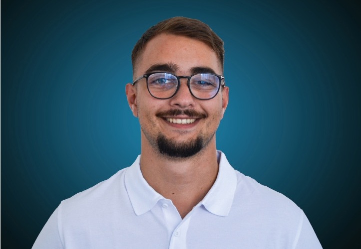 Portraitfoto eines Fachberaters für Bauelemente im Innendienst von CAPITAL Baustoffe vor einem blauem Hintergrund