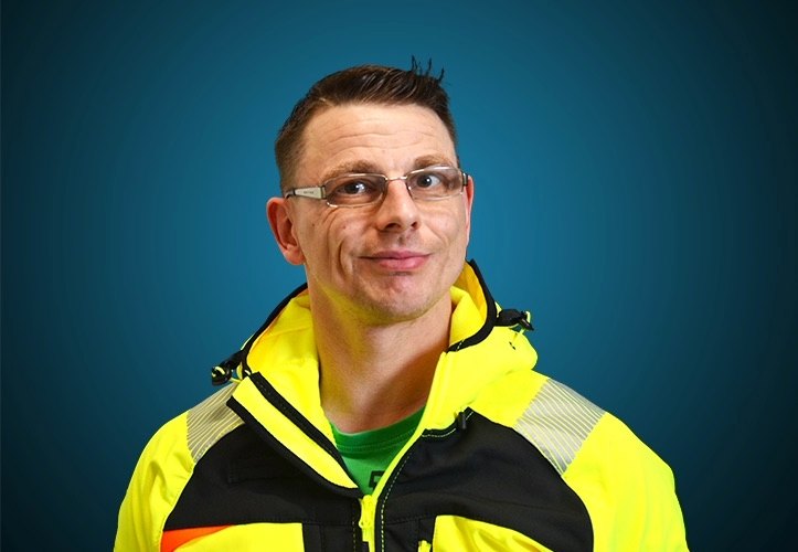 Portraitfoto eines Lagermitarbeiters von CAPITAL Baustoffe vor einem blauem Hintergrund