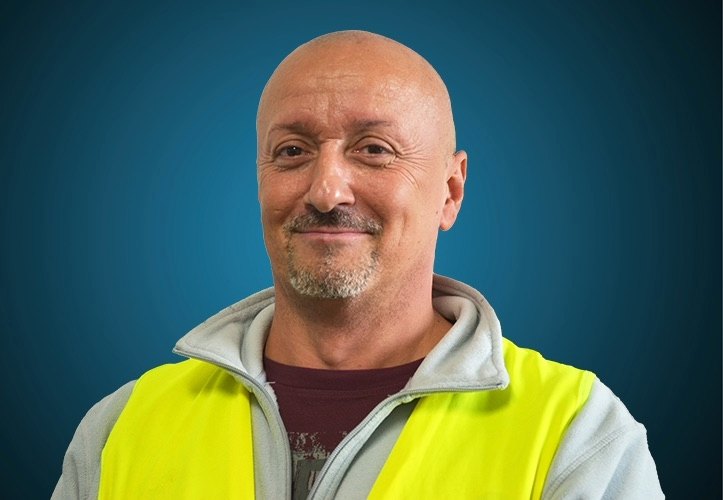Portraitfoto eines Lagermitarbeiters von CAPITAL Baustoffe vor einem blauem Hintergrund