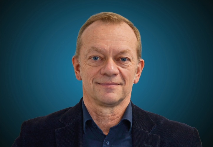 Portraitfoto des Vertriebsleiters Ausbau / Trockenbau von CAPITAL Baustoffe vor einem blauem Hintergrund