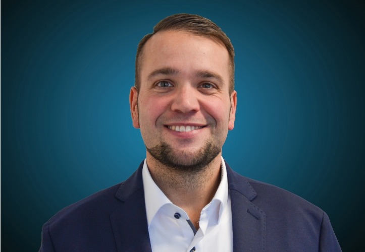 Portraitfoto des Logistikleiters von CAPITAL Baustoffe vor einem blauem Hintergrund