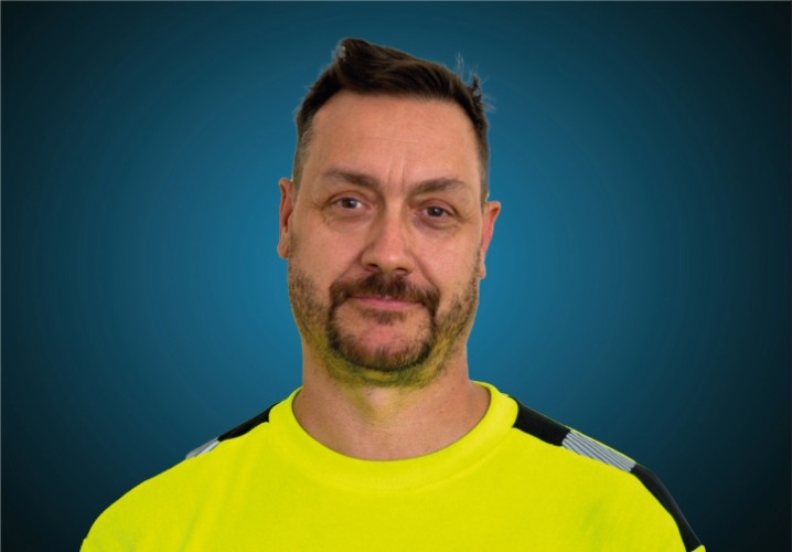 Portraitfoto eines Lagermitarbeiters von CAPITAL Baustoffe vor einem blauem Hintergrund