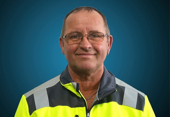 Portraitfoto eines Lagermitarbeiters von CAPITAL Baustoffe vor einem blauem Hintergrund